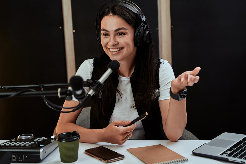 Portait of attractive young female radio host looking emotional while speaking in microphone, moderating a live show